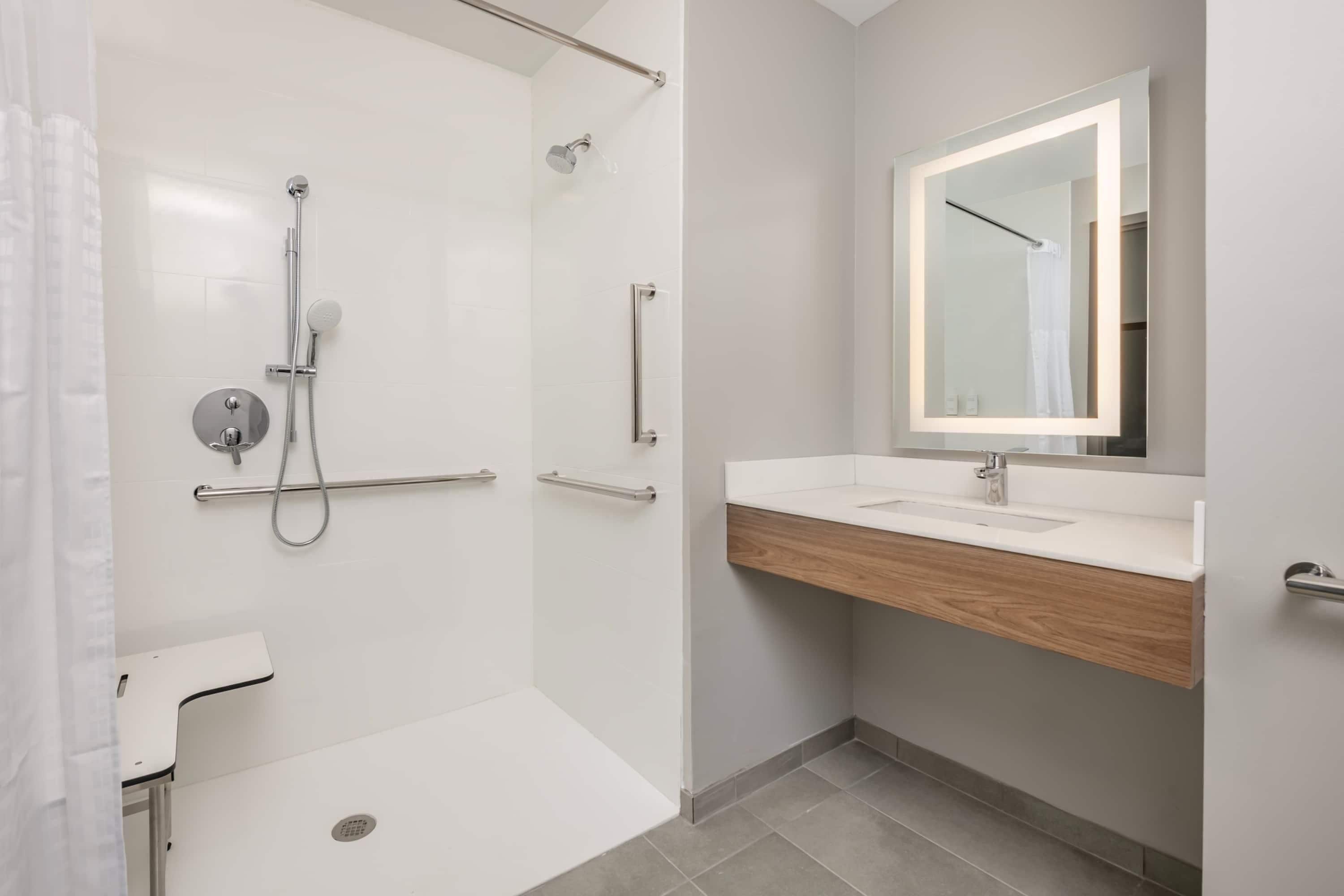 Une salle de bain moderne avec une douche à l’italienne, un meuble-lavabo avec un miroir et des toilettes.