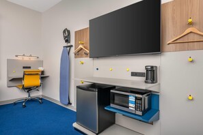 Een functionele kitchenette met een magnetron, koffiezetapparaat en een kleine koelkast.