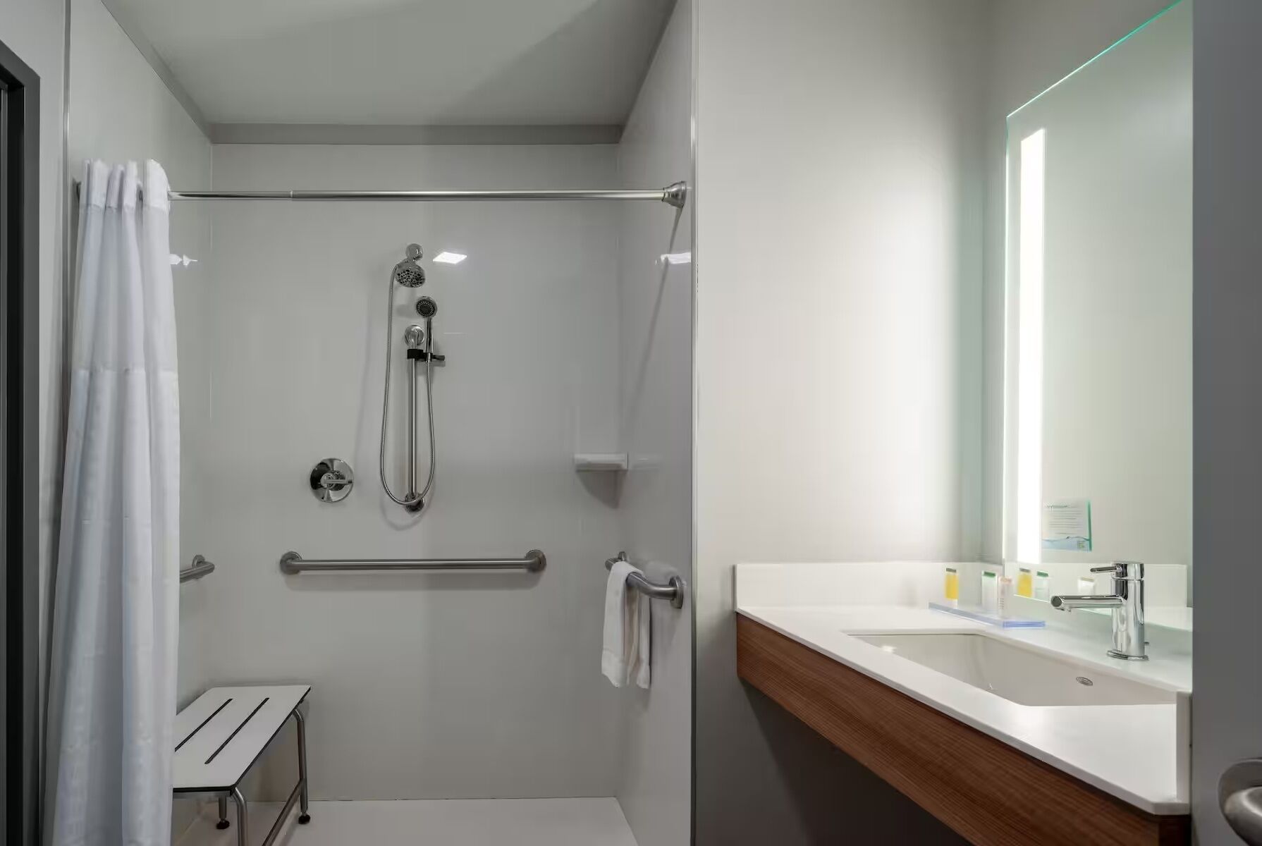 A modern bathroom with a glass-enclosed shower, a wooden vanity, and a large mirror.