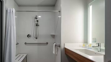 A modern bathroom with a glass-enclosed shower, a wooden vanity, and a large mirror.