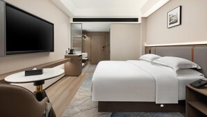 Een hotelkamer met een bed, een televisie, een bureau en een stoel.