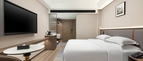 A hotel room with a bed, a TV, a desk, and a chair.