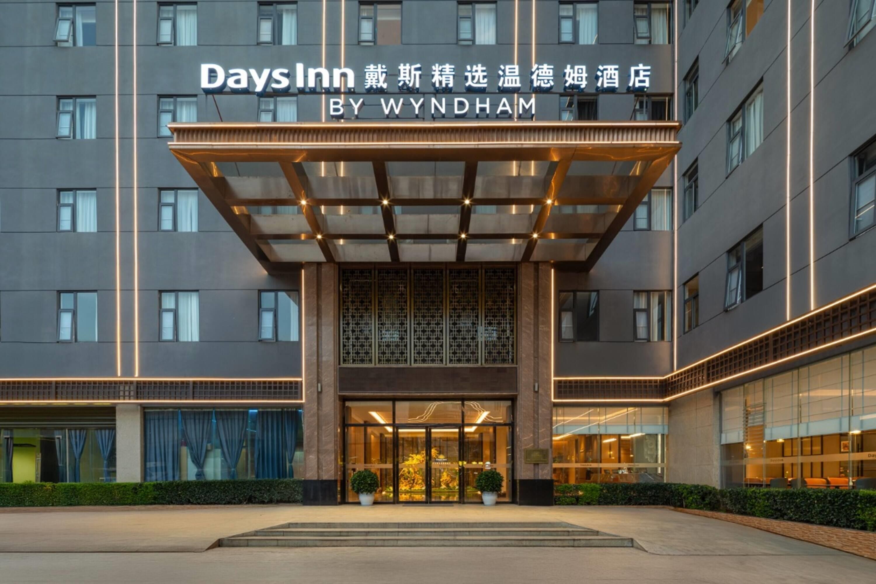 En hotelindgang med en glasfacade, et overdækket område og skiltning for Days Inn by Wyndham.
