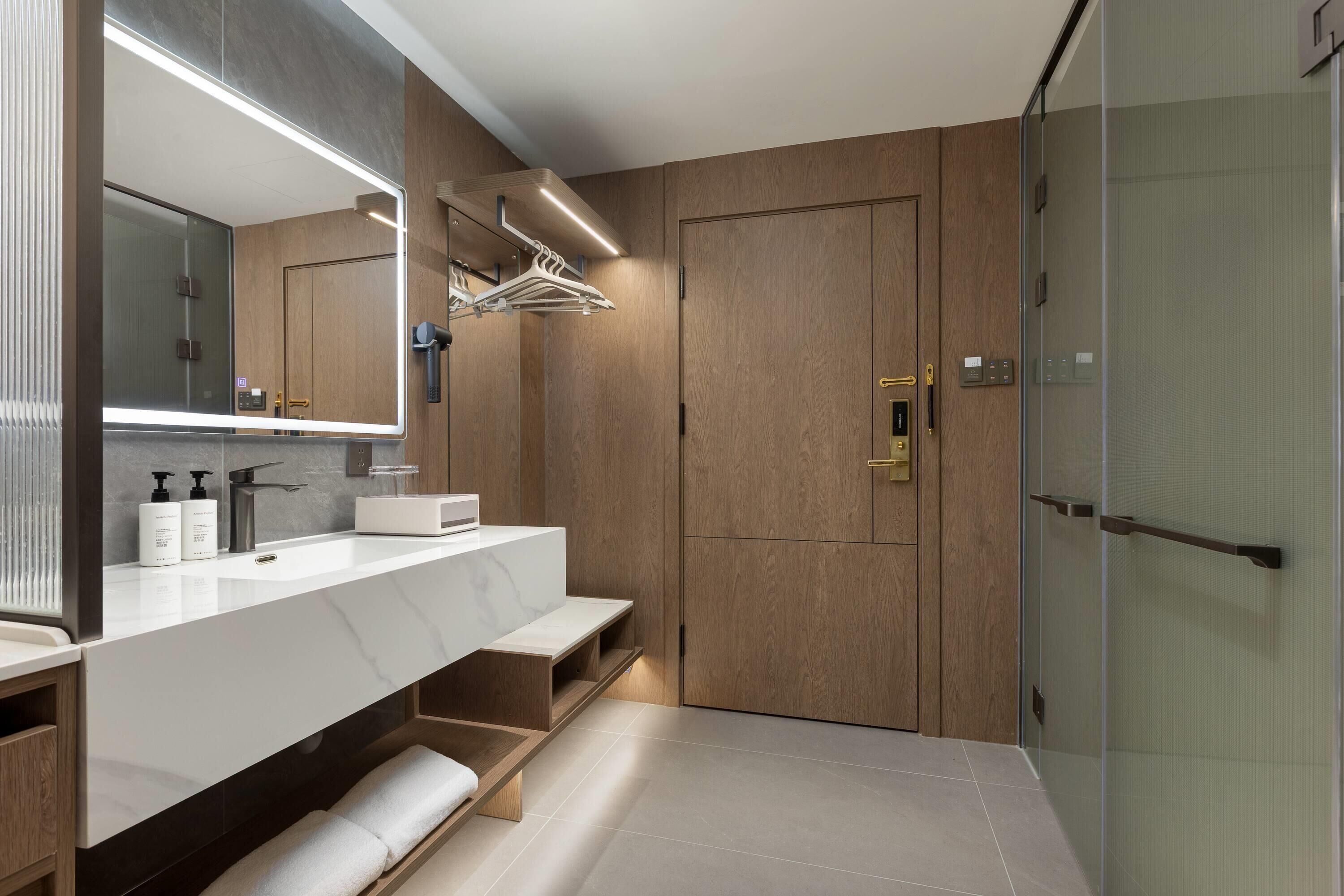 A modern bathroom with a large mirror, dual sinks, and a walk-in shower.