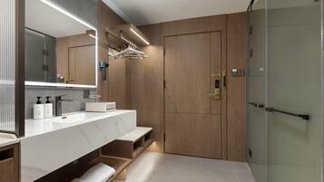 A modern bathroom with a large mirror, dual sinks, and a walk-in shower.