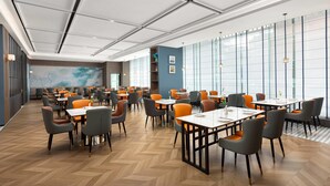 Een moderne eetruimte met tafels en stoelen, grote ramen en een visgraatmotief houten vloer.