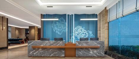 A reception area with a marble counter, a large floral mural, and a glass wall with a view.