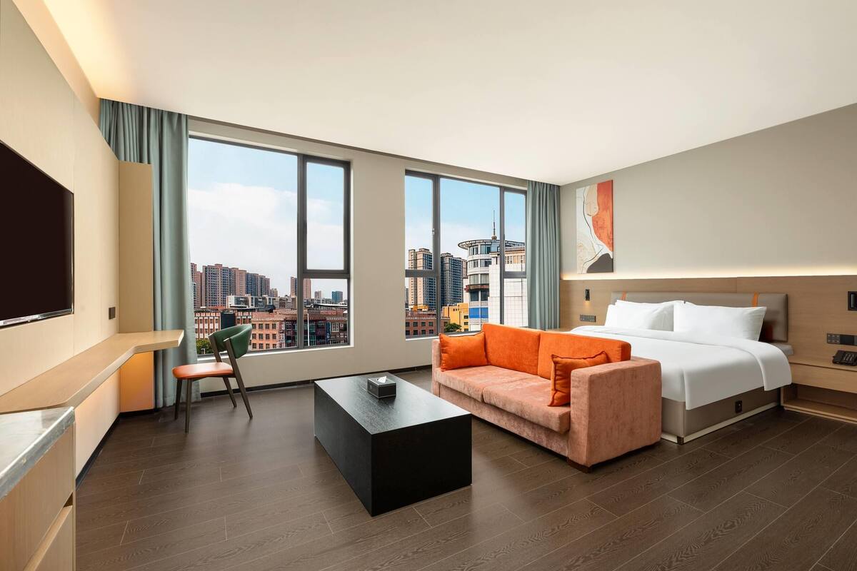 Een moderne hotelkamer met een groot raam, een bed, een bureau en een stoel.