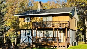 Une maison en bois à deux étages, dotée d’un balcon, d’une cheminée et d’un porche à l’avant.