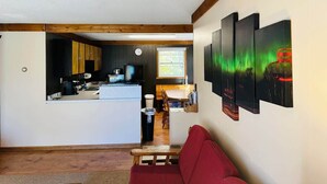 Un espace de vie compact comprenant une cuisine, un coin repas et un canapé rouge.
