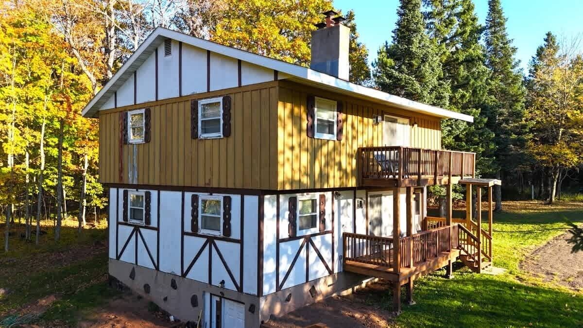 A cabin with a balcony, a chimney, and a deck.