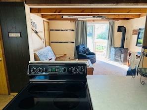 A kitchen with a stove, a dining table, and a view of a living area with a couch and a TV.