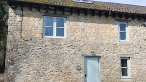 Un edificio de piedra con una puerta y dos ventanas.