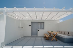 A covered outdoor area with a door, a bench, and a sofa. - Caldera's Elements (Santorini)