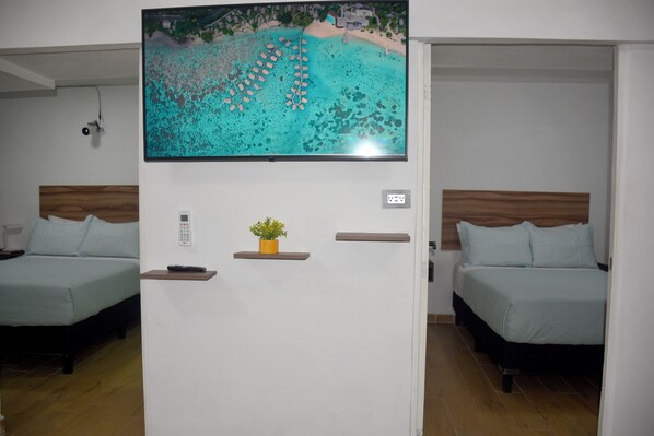 A hotel room with two beds, a TV mounted on a wall, a small plant on a shelf, and a wooden headboard. - Great magic, 5 minutes from the sea! Ideal apartment for families of 4 people. (cancun)