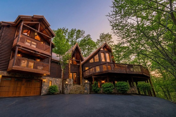 Grand log cabin exterior surrounded by trees, setting the scene for a spacious mountain retreat and unforgettable group vacation