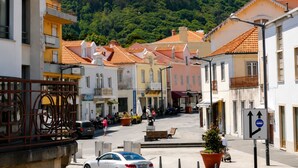 A street with buildings, a hill with greenery, and a clear sky. - Casa Azul Hostel (Sintra)