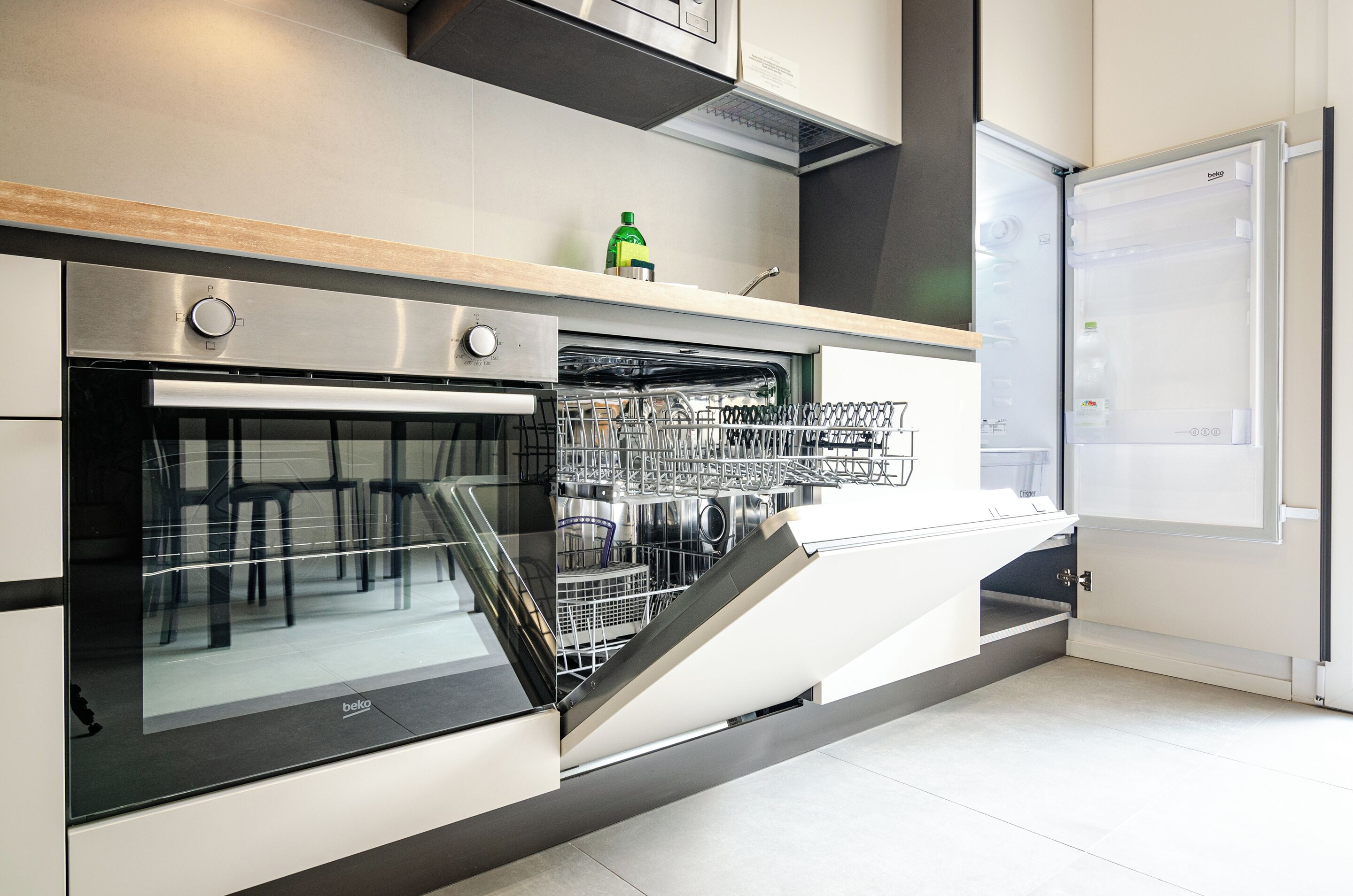 Una cocina moderna con electrodomésticos integrados, incluyendo horno y lavavajillas, y un refrigerador con congelador.