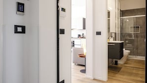 A modern interior with a visible door labeled 'LOFT 6,' a shower area, and a kitchen in the background.