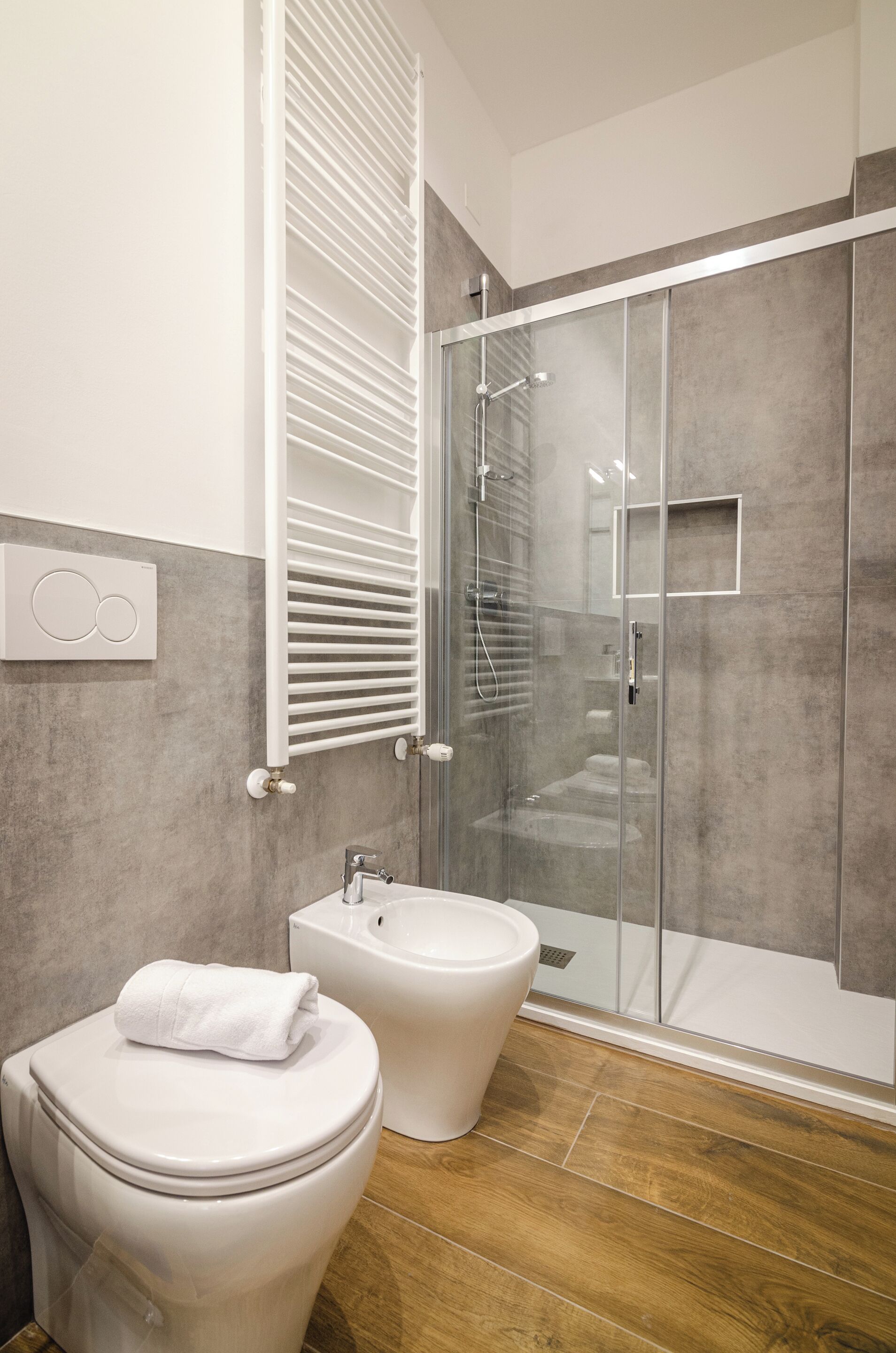 A modern bathroom with a toilet, bidet, and glass-enclosed shower.