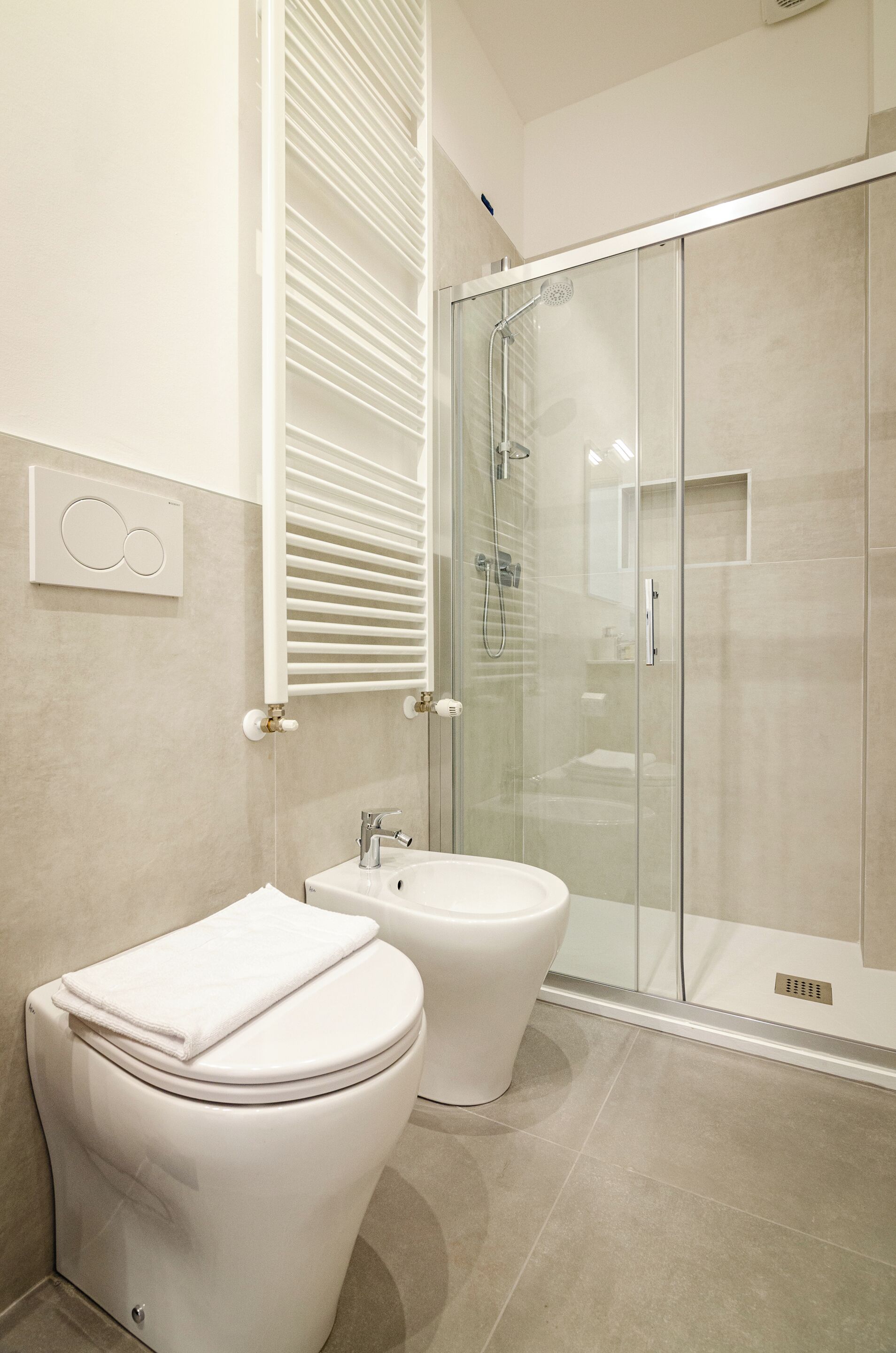 A modern bathroom with a toilet, bidet, and glass-enclosed shower.