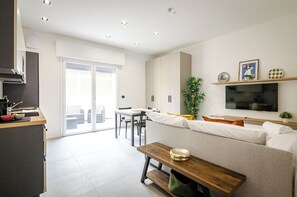 Una cocina moderna con comedor, un sofá y un televisor montado en la pared.
