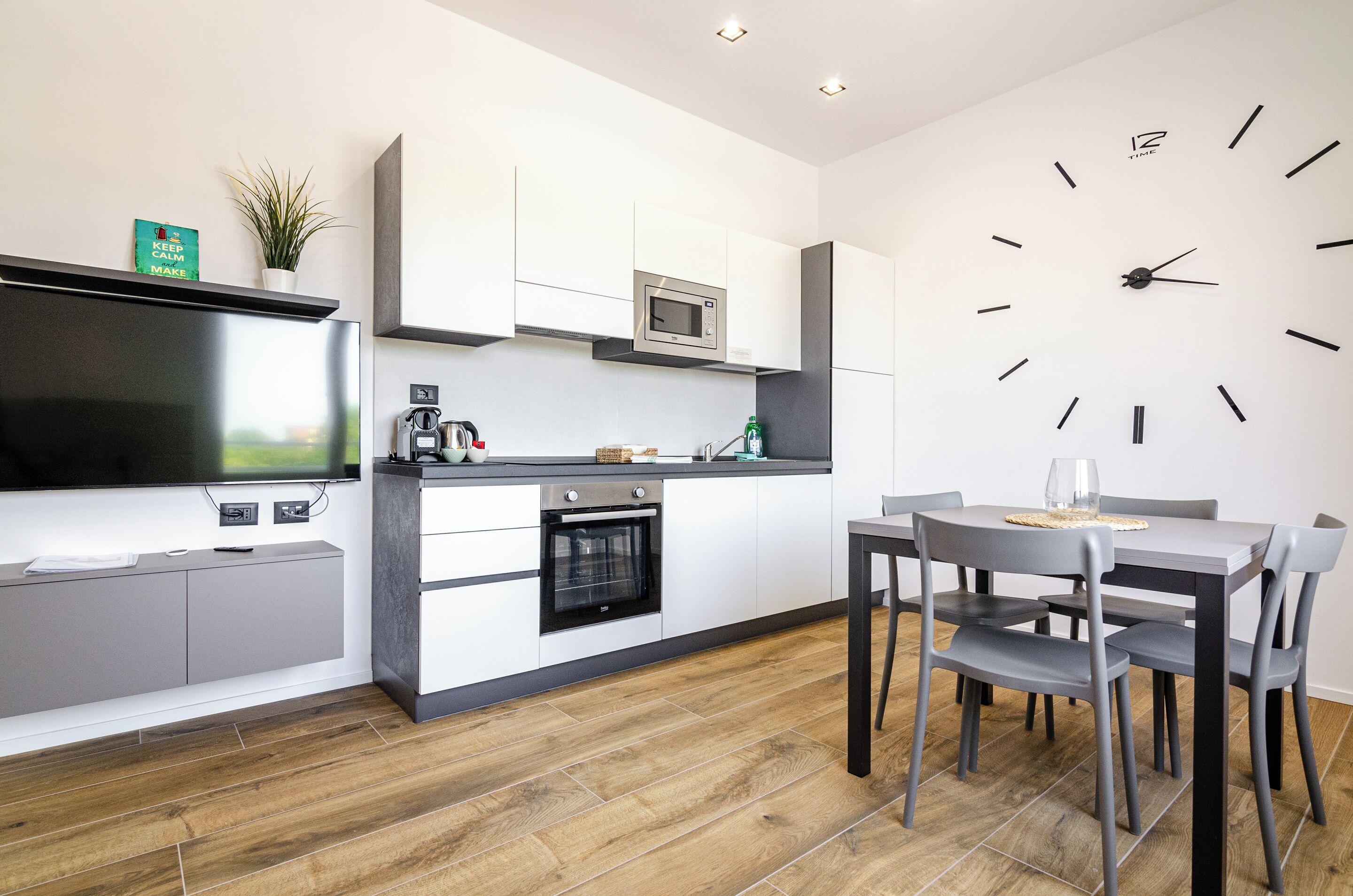 A modern kitchen with a built-in microwave, oven, and a dining area with a table and chairs.