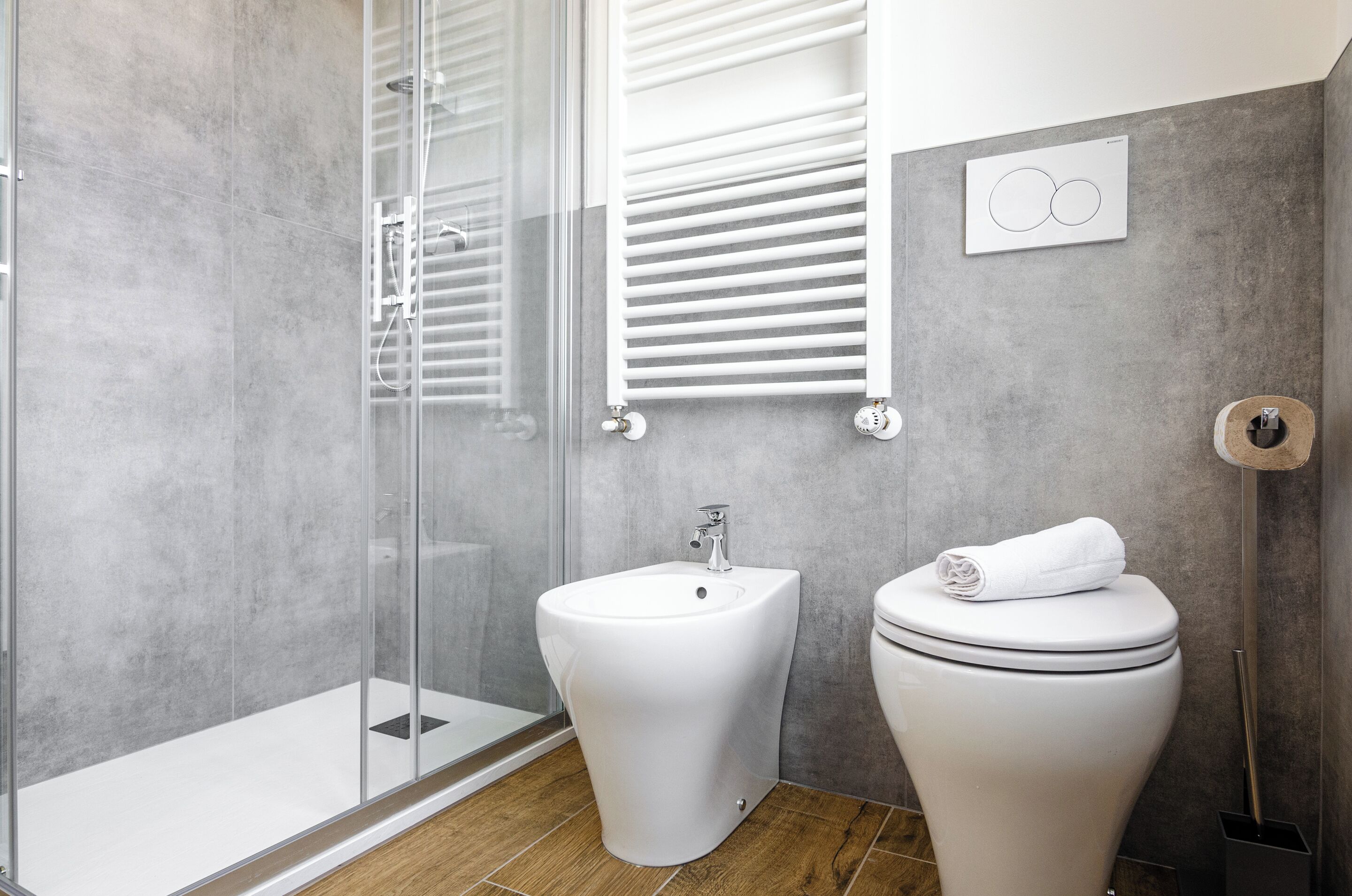A modern bathroom with a glass-enclosed shower, a bidet, and a toilet.