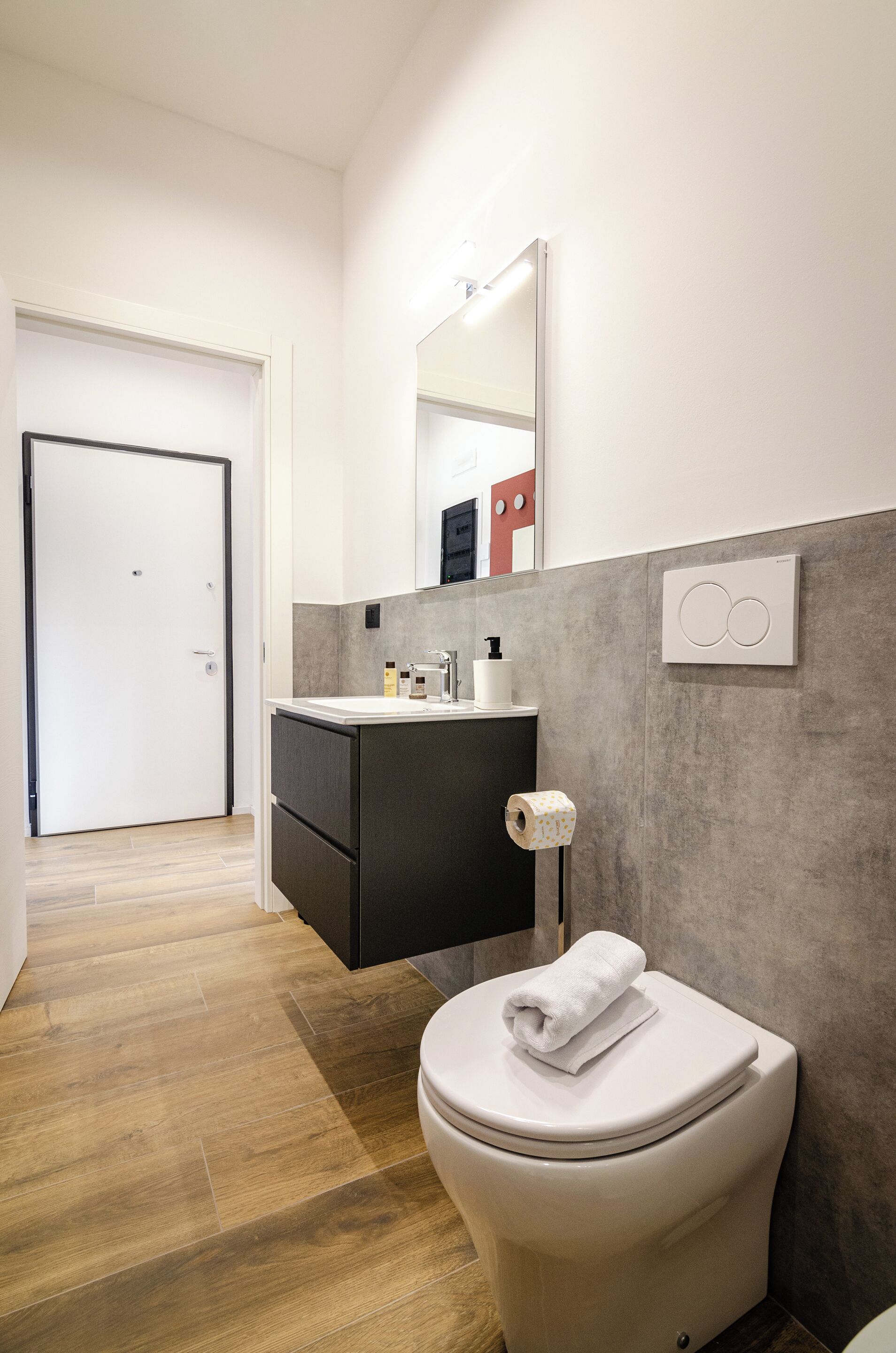 A modern bathroom with a toilet, sink, and mirror.