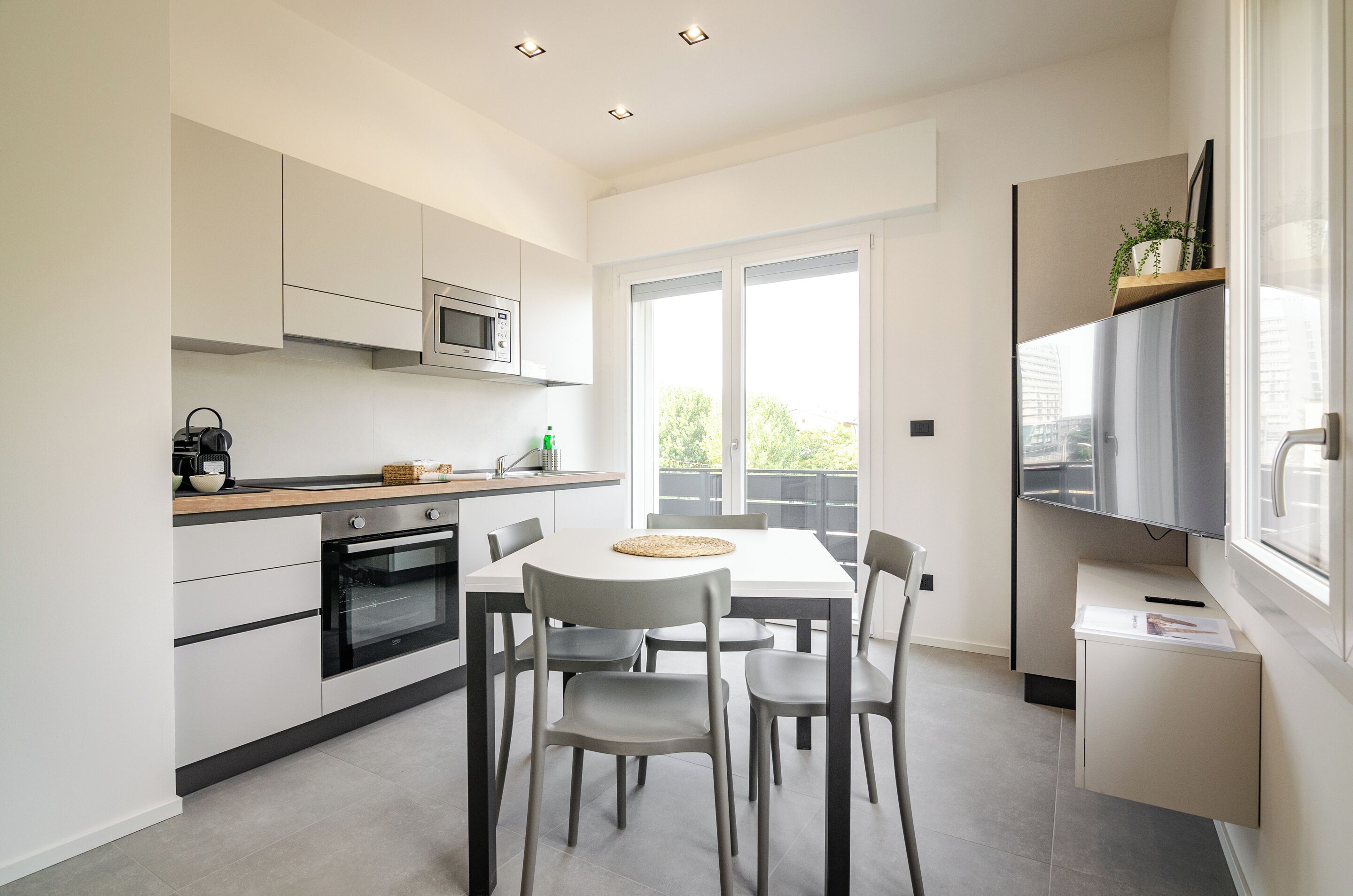 A modern kitchen with a dining area, built-in appliances, and a large window.