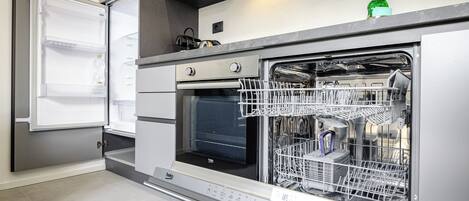 A modern kitchen with a built-in dishwasher, an oven, and a refrigerator.