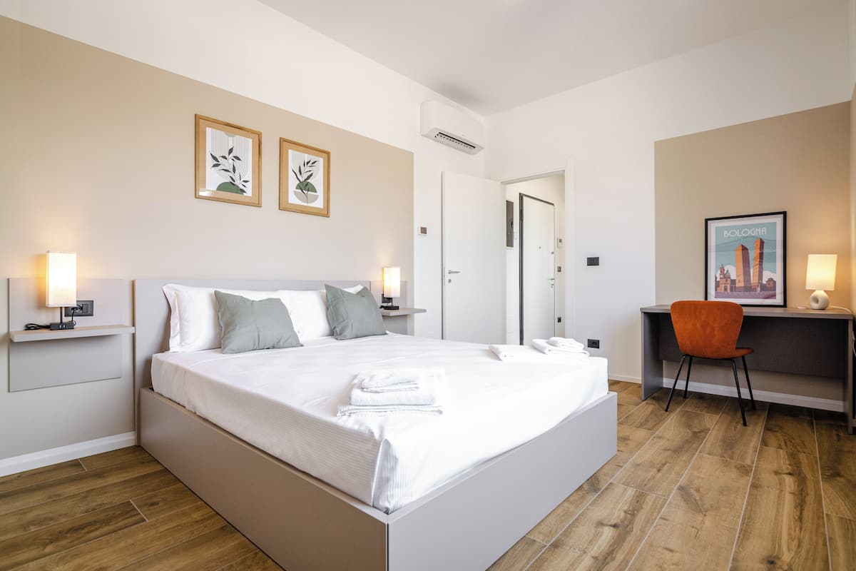 A modern hotel room with a large bed, bedside tables, a desk, and a chair.