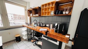 A modern kitchen with a wooden countertop, built-in shelves, and a dishwasher. - Central spacious apartment with roof terrace! (Bochum)