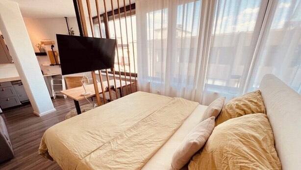 Hotellihuone, jossa on sänky, työpöytä, tuoli ja televisio.