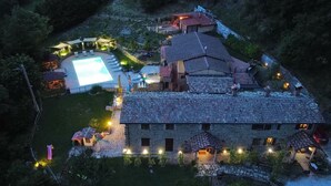 An aerial view of a stone building with multiple rooms, a swimming pool, and outdoor lighting. - Room in typical farmhouse, nestled in the green hills of Gubbio (Gubbio)