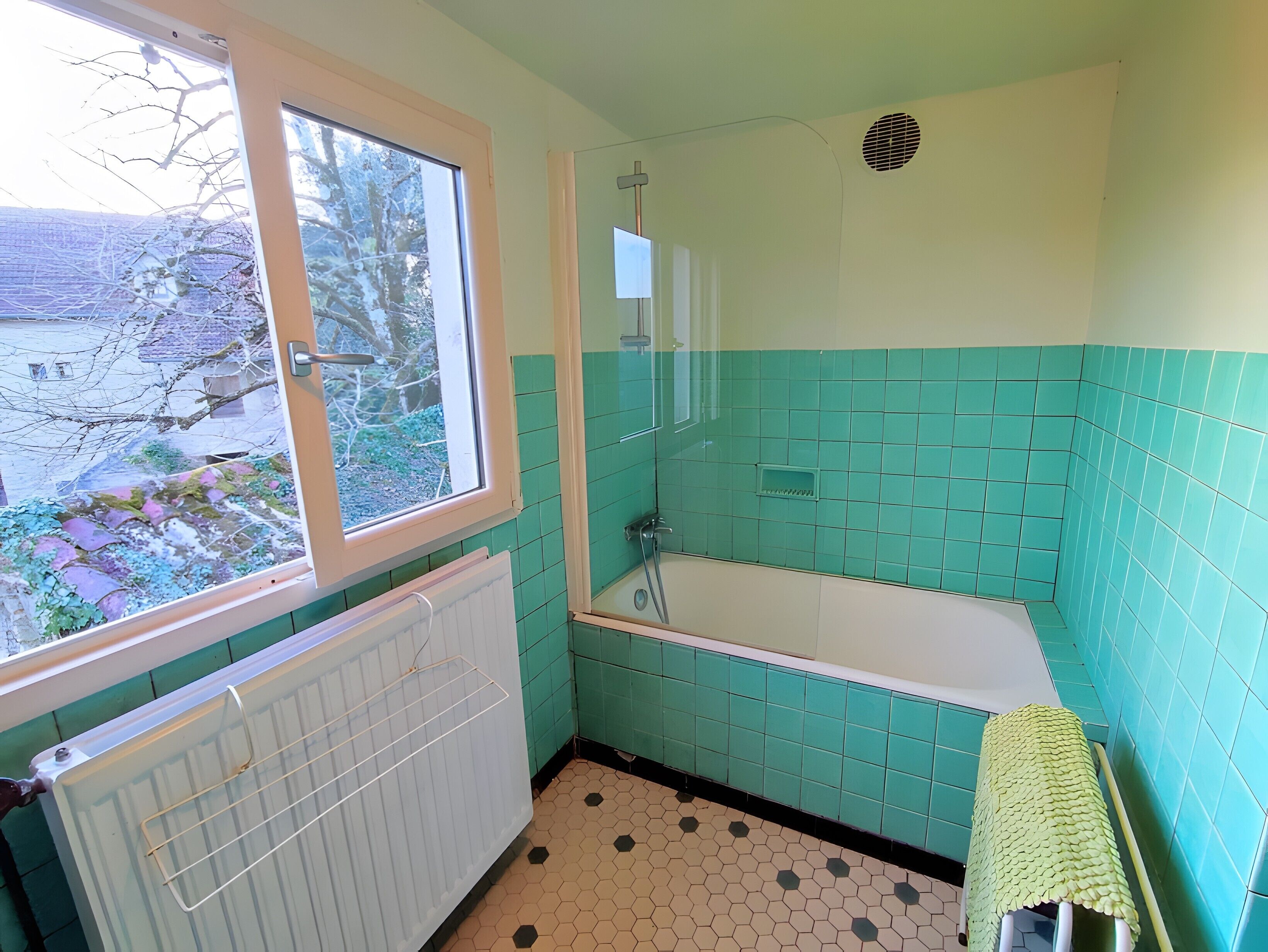 Ein Badezimmer mit Badewanne, Fenster und Heizkörper.