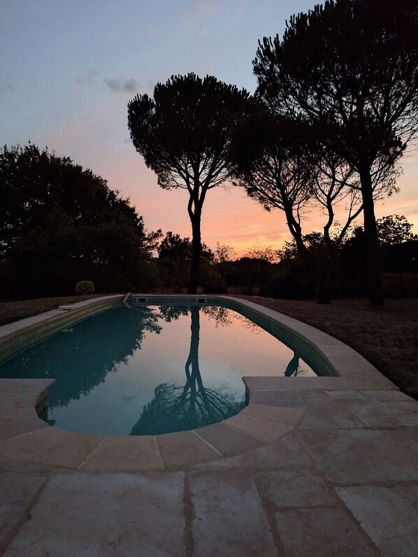 A swimming pool with a curved edge, surrounded by stone tiles.