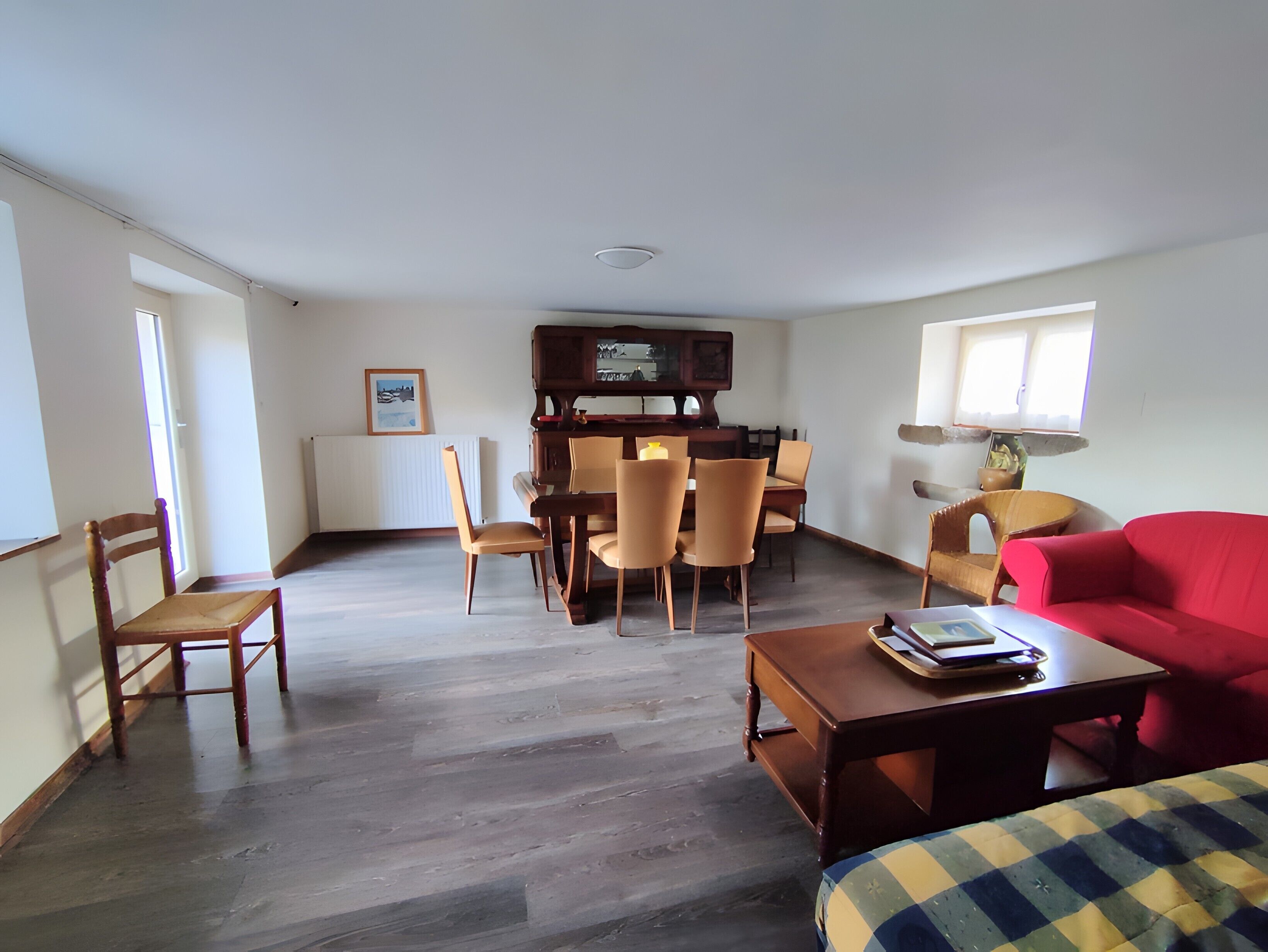 A living room with a dining area, a red sofa, and a television.
