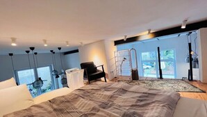 A modern bedroom with a large bed, a chair, a window, and a view of the outside.