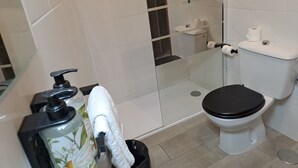 A modern bathroom with a toilet, shower, and sink. - Nest Flats Navas (Granada)