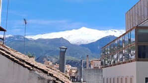 Un bâtiment moderne à la façade de verre, une montagne aux sommets enneigés en arrière-plan et un ciel bleu dégagé.