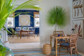 A dining area with a table, chairs, and a large potted plant. - Sitting Pretty - Private Beachfront Retreat Fully Staffed with Chef (Dunmore Town)