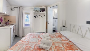 Une chambre à coucher avec un lit, une table de chevet, une armoire et une salle de bain visible à travers une porte ouverte.