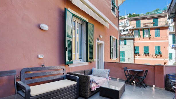 Un balcon extérieur aménagé avec des meubles en osier, une table et des chaises.