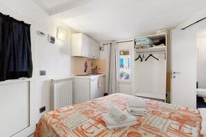 Een slaapkamer met een bed, kast, raam en een badkamer.