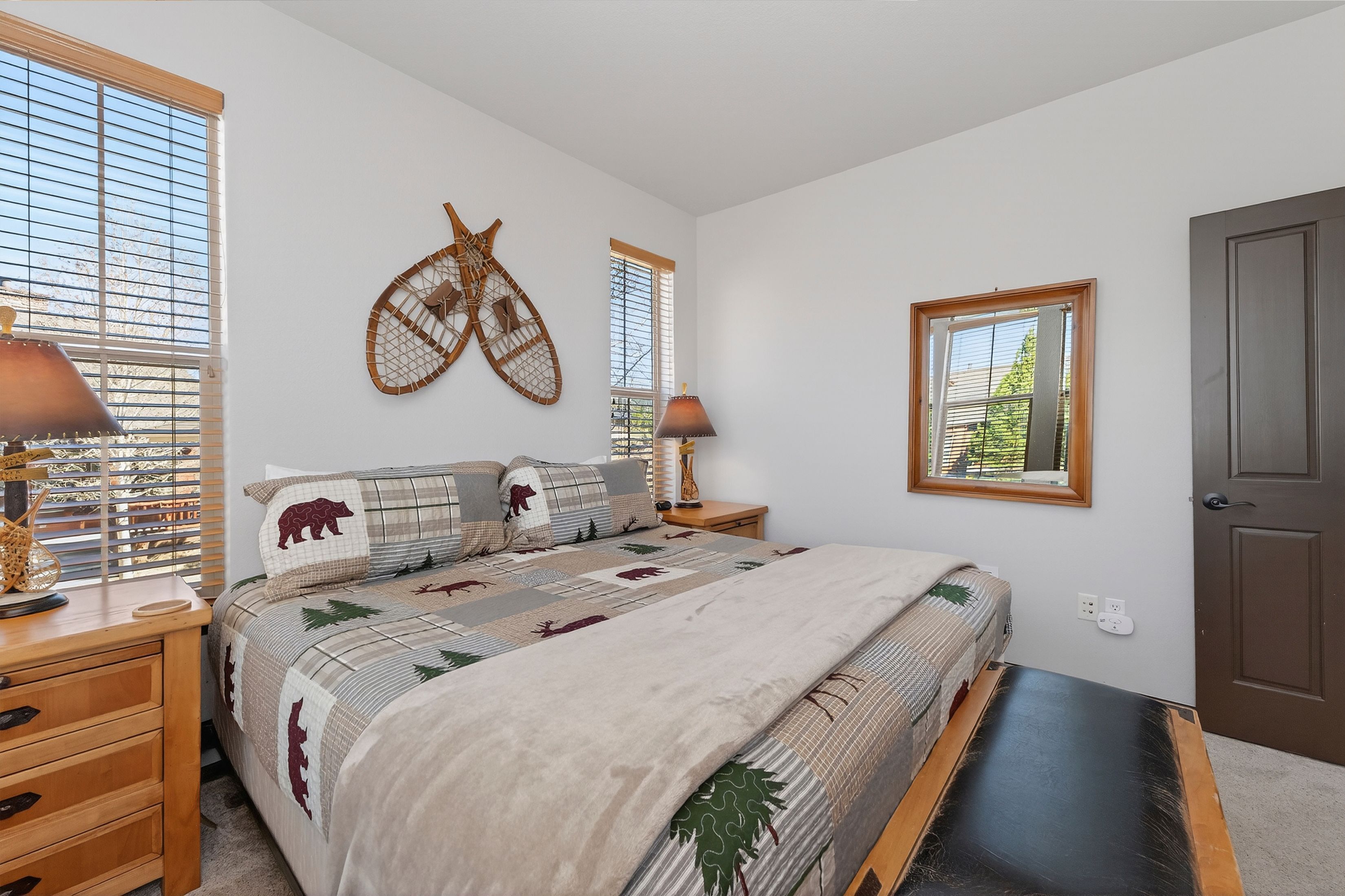 A bedroom with a bed, two bedside tables, a wall-mounted decorative item, a window, and a door.