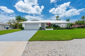 A single-story house with a garage, surrounded by a well-maintained lawn and small trees. - Barefoot Escape (Fort Myers Beach)