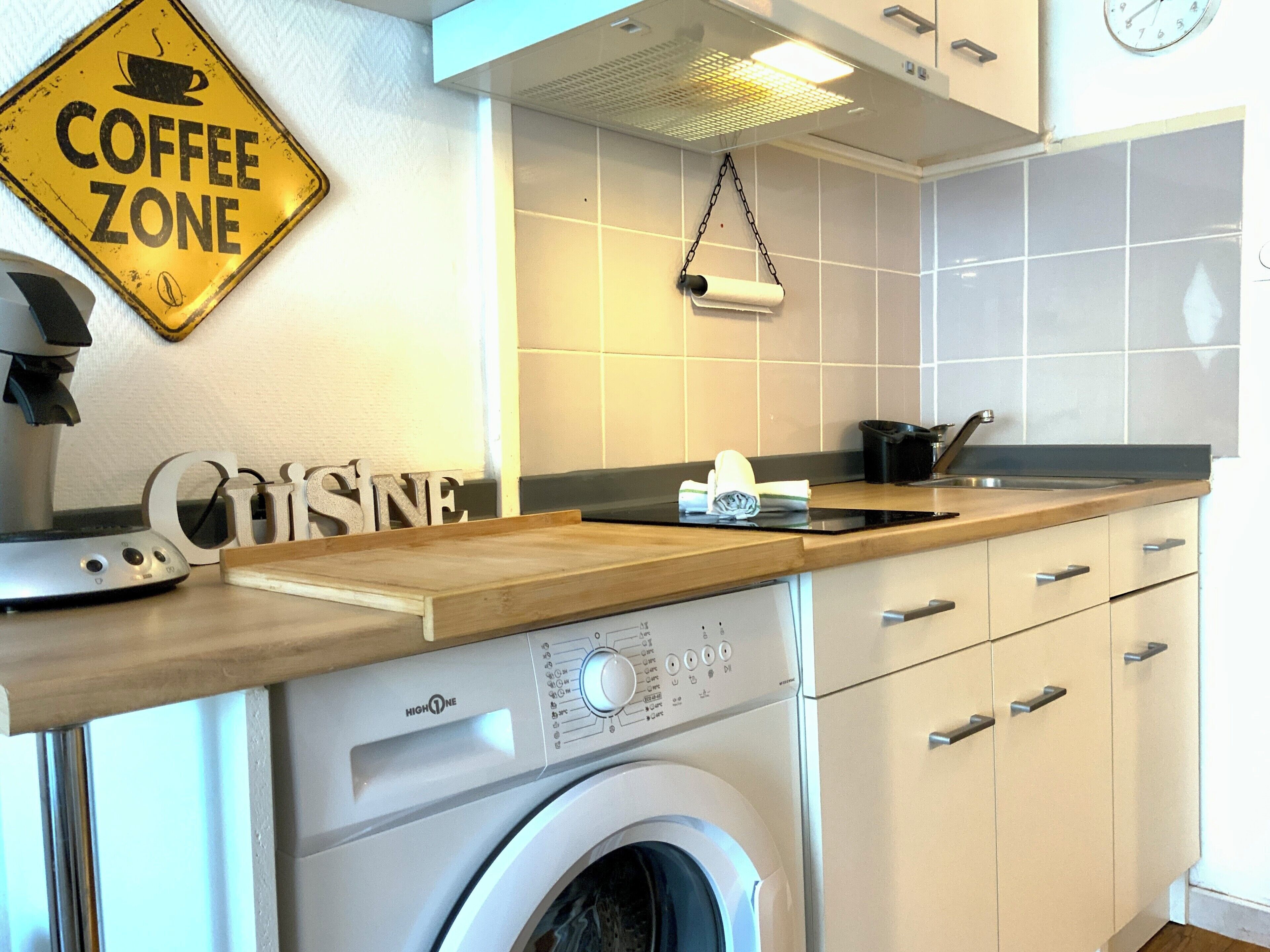 A kitchen with a coffee zone sign, a washing machine, and a sink.