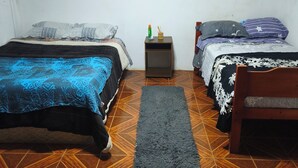 A room with two beds, a small table, and a rug.