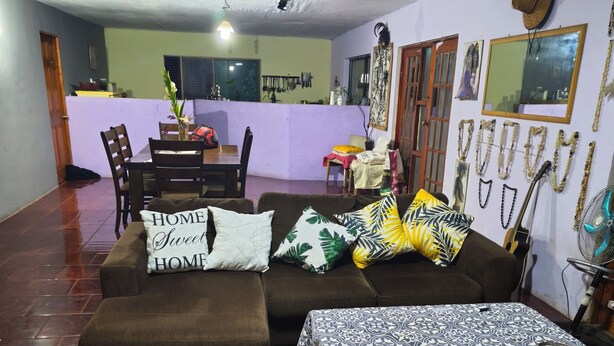A living room with a sofa, a dining table, and a kitchen area in the background.